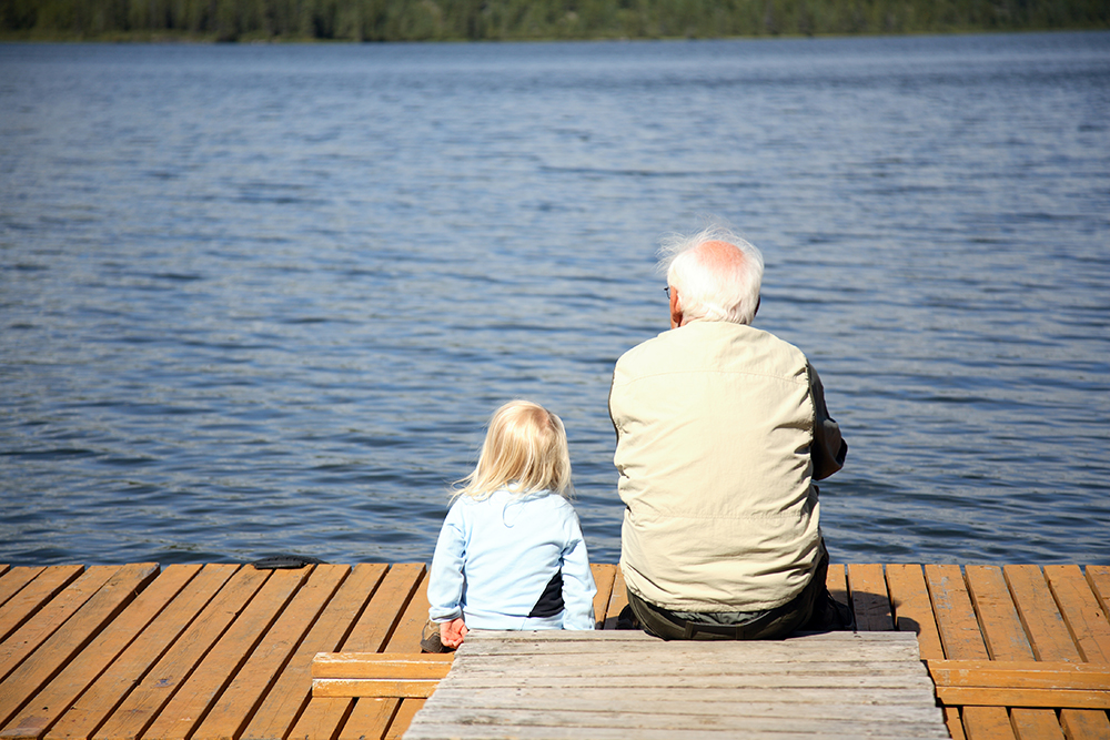 Grossvater sitzt mit Enkel am See