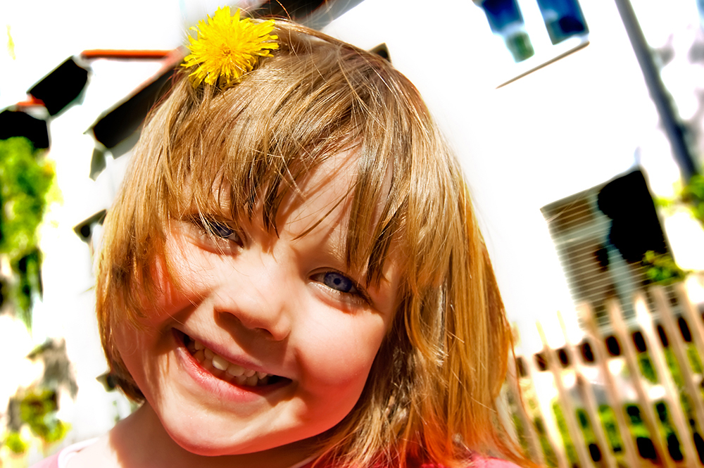 Lachendes Maedchen mit einer gelben Blume im Haar